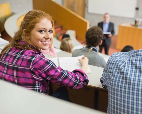 female student in lecture hall taking notes for ap class