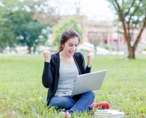 girl looking at her laptop and cheering